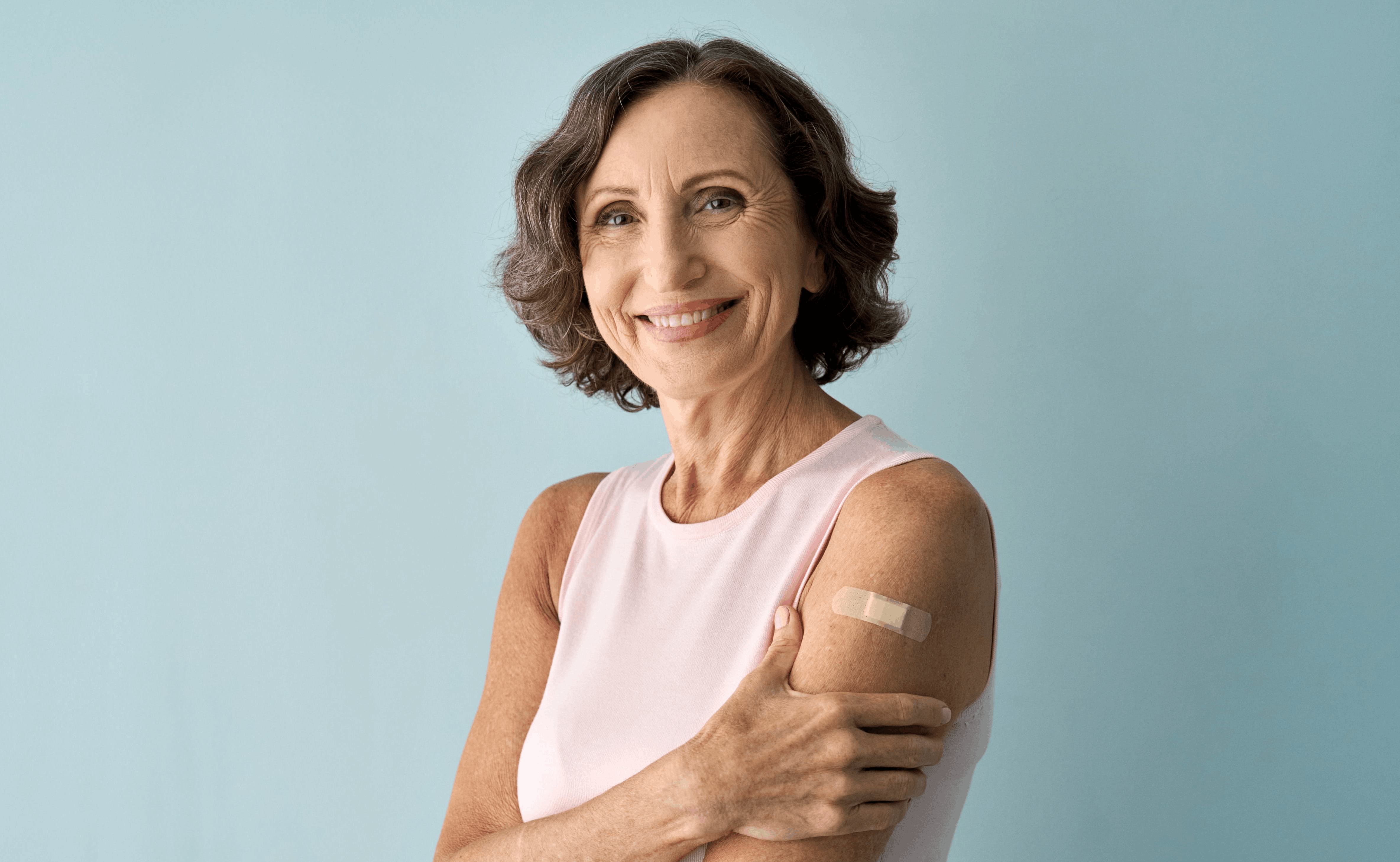Smiling healthy mature older senior happy woman showing bandage on arm (1)